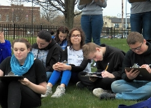 Students writing on their notes at a field day activity held by Michigan Environmental Education Curriculum Support